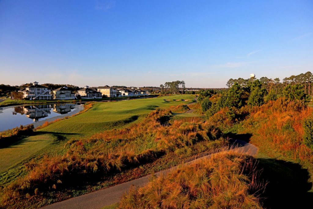 View of golf course in front of pond and houses