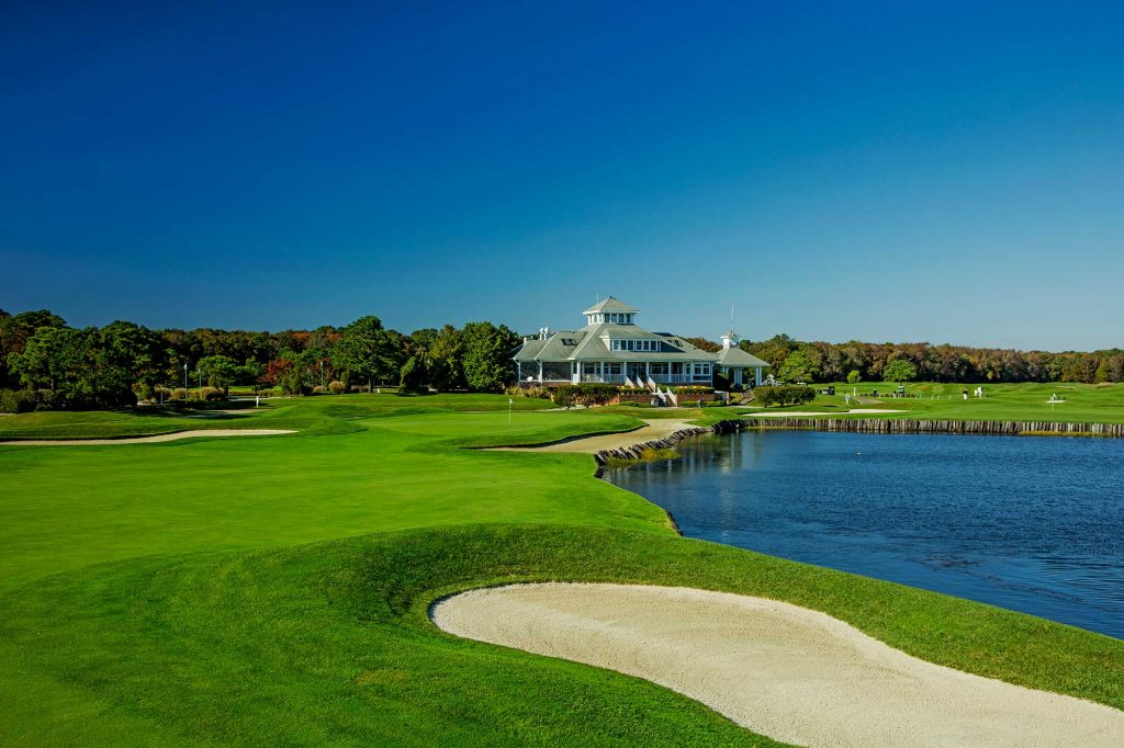 Golf course next to pond and house